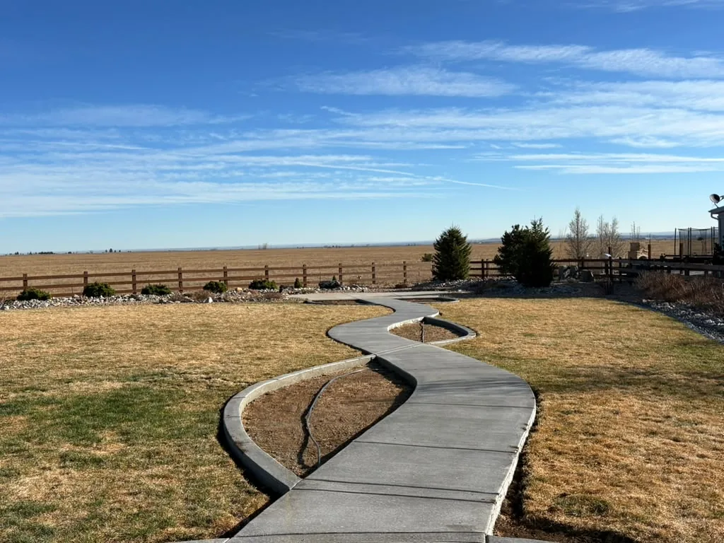Winding concrete walkway with curved flower-bed borders